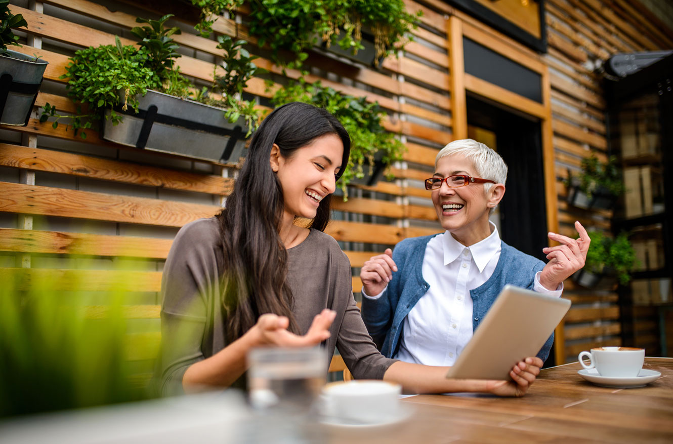 Two women using tablet outdoors